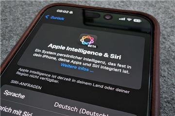 Das Handy, ein iPhone, liegt auf einem Tisch. Auf dem Bildschirm sind unter anderem die Worte "Apple Intelligence" und "Siri" zu lesen. Mit iOS 18.4 startet Apple Intelligence auch in Deutschland. Die neue KI soll helfen – doch sie läuft nur auf neueren Geräten, und beim Datenschutz bleiben Fragen offen.