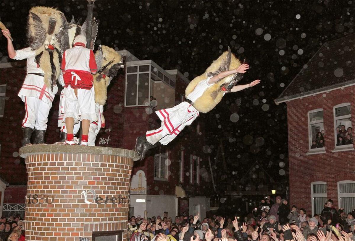 „Klaasohm“ auf Borkum: Frauen schlagen als Volksfest? Mit Masken verkleidete Männer des Vereins Borkumer Jungens stürzen sich am Abend (Aufnahme vom 05.12.2011) beim traditionellen Klaasohm-Fest von einem Podest.