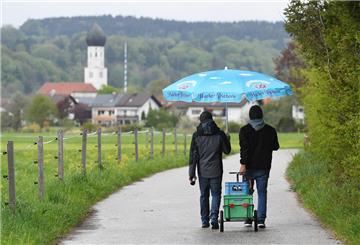 Zwei junge Väter ziehen einen mit Bier beladenen Anhänger an Vatertag durch die Natur. 