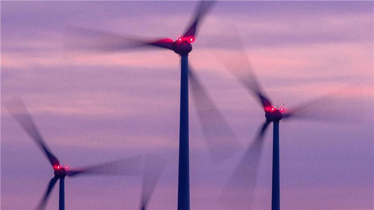 Mit Signallampen beleuchtete Windräder drehen sich nach Sonnenuntergang.