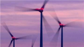 Mit Signallampen beleuchtete Windräder drehen sich nach Sonnenuntergang.
