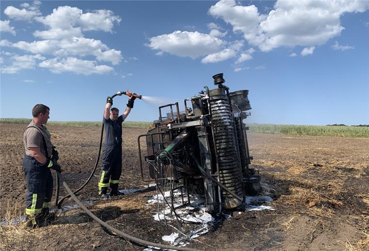 Mit vereinten Kräften gegen den Brand: Einsatzkräfte aus Midlum und Wanhöden löschen das Feuer, das eine Rundballenpresse und weite Ackerflächen in Midlum entzündet hat.