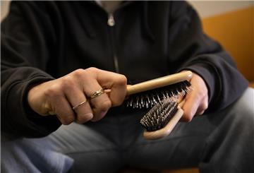 Ein Mann hat zwei Haarbürsten in der Hand. 