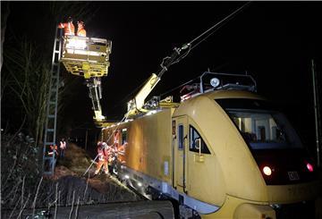 Mitarbeiter der Deutschen Bahn stehen auf einem speziellen Triebfahrzeug zur Instandhaltung von Oberleitungen und reparieren den stromführenden Strang. Durch die Stürme wurde ein Baum umgedrückt, der auf die Oberleitung fiel und diese Reparatur notwendig machte