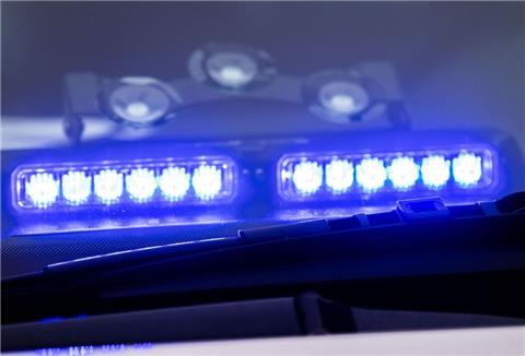 Ein Blaulicht leuchtet unter der Frontscheibe eines Einsatzfahrzeugs der Polizei.