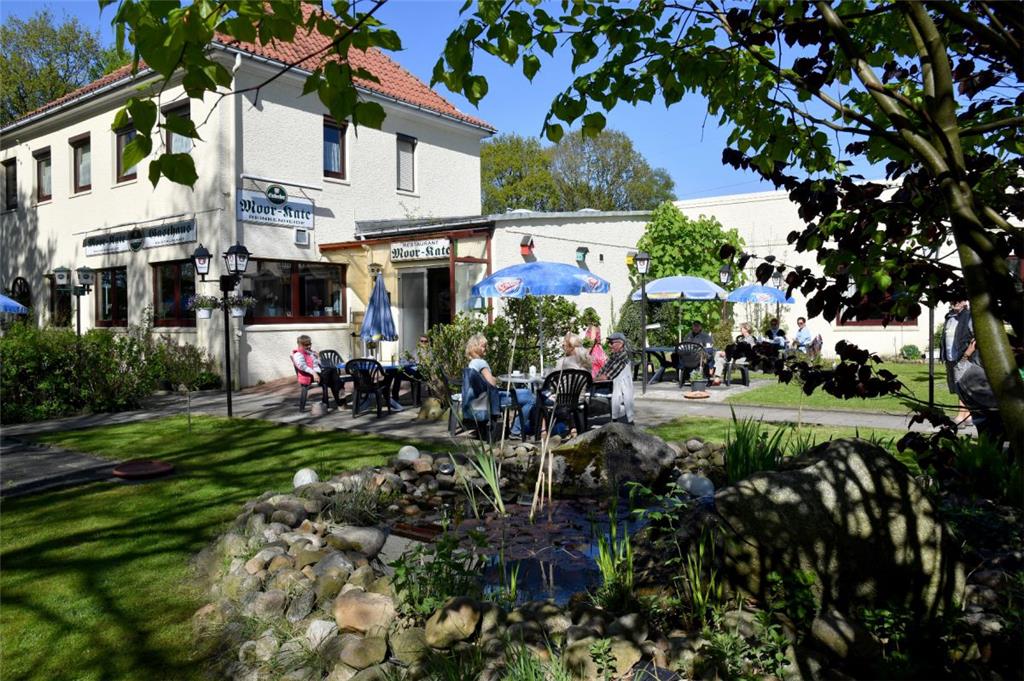 Mitten im Grünen: Am Höllenhammsweg in Schiffdorferdamm gibt es viele grüne Felder, ein paar Häuser und: die Moorkate. Ein gut bürgerliches Restaurant mit kleinem, aber gemütlichem Biergarten. Zwischen Bäumen, Rasen und Blumenbeeten kann man hier speisen oder einfach ein Getränk genießen.