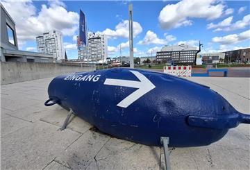 Eine blaue Fahrwassertonne mit dem Schriftzug "Eingang" und einem großen Pfeil.