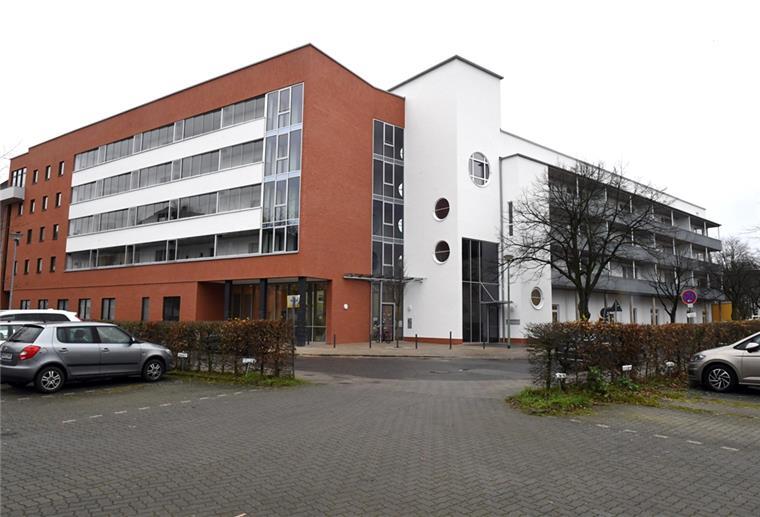 Blick auf ein Mehrfamilienhaus, im Vordergrund ein Parkplatz mit Autos. Modellprojekt für Bremerhaven: Katholische Kita und Wohnungen in einem Gebäude.