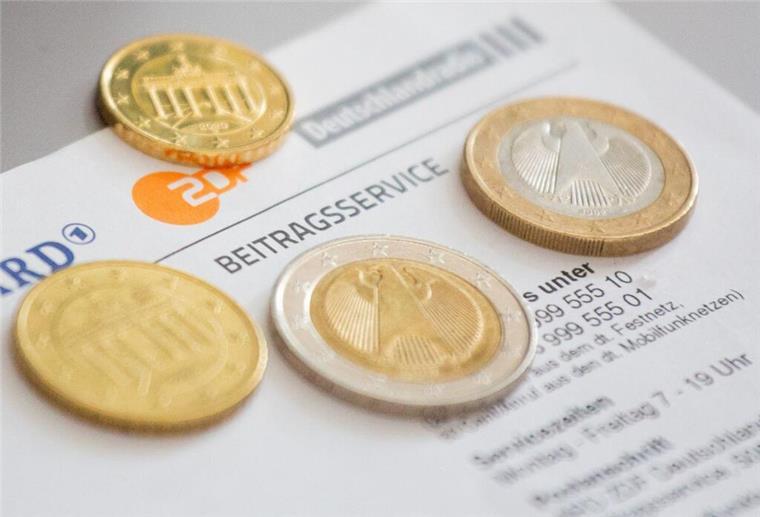Geldmünzen liegen auf einem Schreiben zum Rundfunkbeitrag. Monatlich über 18 Euro Rundfunkbeitrag? Das stößt vielen Bürgern sauer auf. Mit einem Antrag kann man sich vom Zwangsbeitrag befreien lassen.