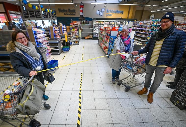 Monika Miesner (links) und Anja Neumann mit Thomas Gries zeigen im E-Center Rotersand, was zwei Meter Abstand im Alltag im Supermarkt bedeuten.