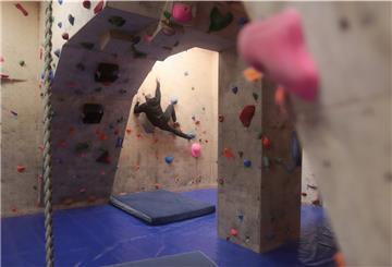 Ein Blick in die Boulderhalle: Ein Mann klettert gerade eine Wand hinauf.