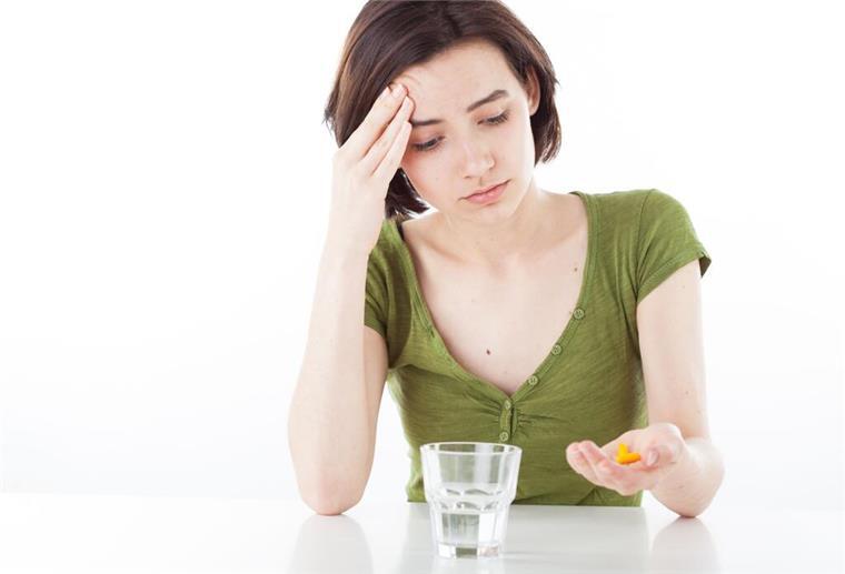 Schlapp, müde, kraftlos? Dahinter steckt oft ein Mangel an Vitaminen Eine Frau sitzt vor einem Glas Wasser.