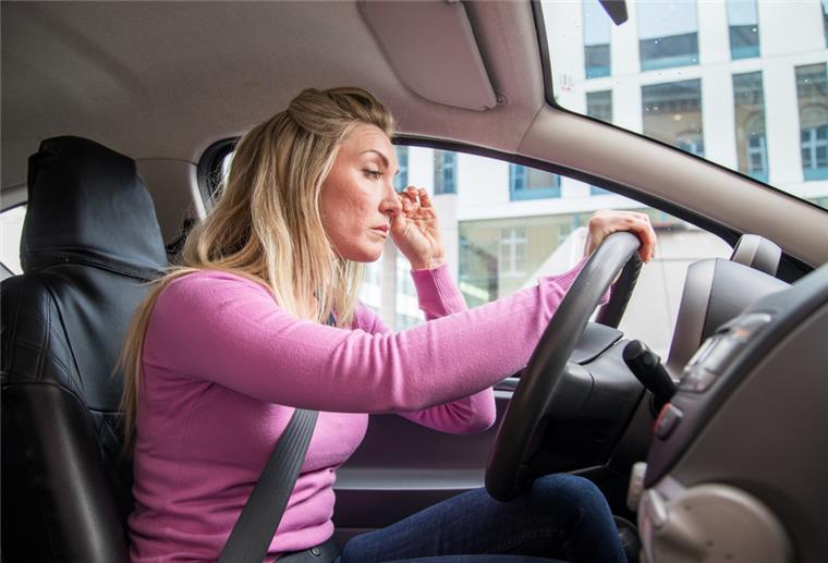 TÜV: Gefährlicher Sekundenschlaf - Warnsignale nicht ignorieren Frau sitzt müde am Steuer eines Autos