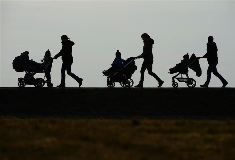 In einem Schattenrist ist zu sehen, wie drei Erwachsene jeweils einen Kinderwagen schieben, in dem Kinder sitzen.