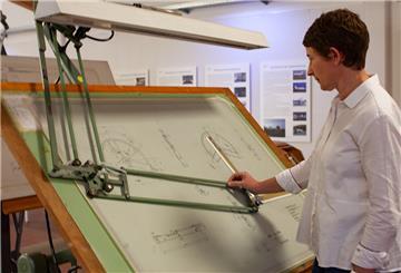 Museumsleiterin Dr. Anja Dörfer steht an einem Original-Zeichentisch, an dem einst Flugzeugteile für die VFW 614 konstruiert worden sind.