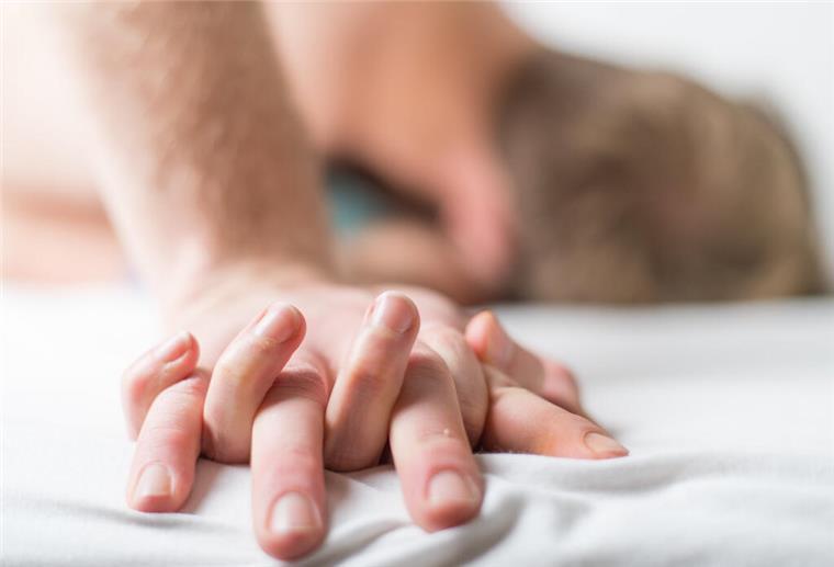 Welche Musik hören die Deutschen eigentlich im Schlafzimmer? Ein junges Paar liegt im Bett.