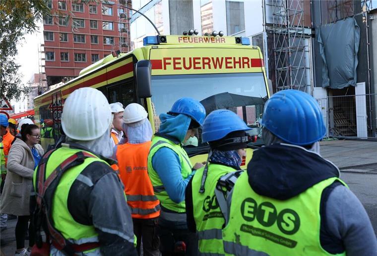  Einsatzfahrzeuge der Feuerwehr und Bauarbeiter stehen vor einer Baustelle. 