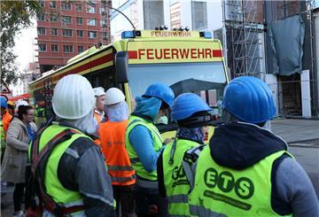 Einsatzfahrzeuge der Feuerwehr und Bauarbeiter stehen vor einer Baustelle. 