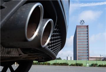 Auspuffrohre eines Volkswagens fotografiert mit dem Markenhochhaus am VW Werk Wolfsburg.