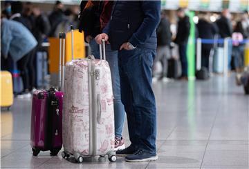 Zwei Personen mit Koffern am Flughafen.