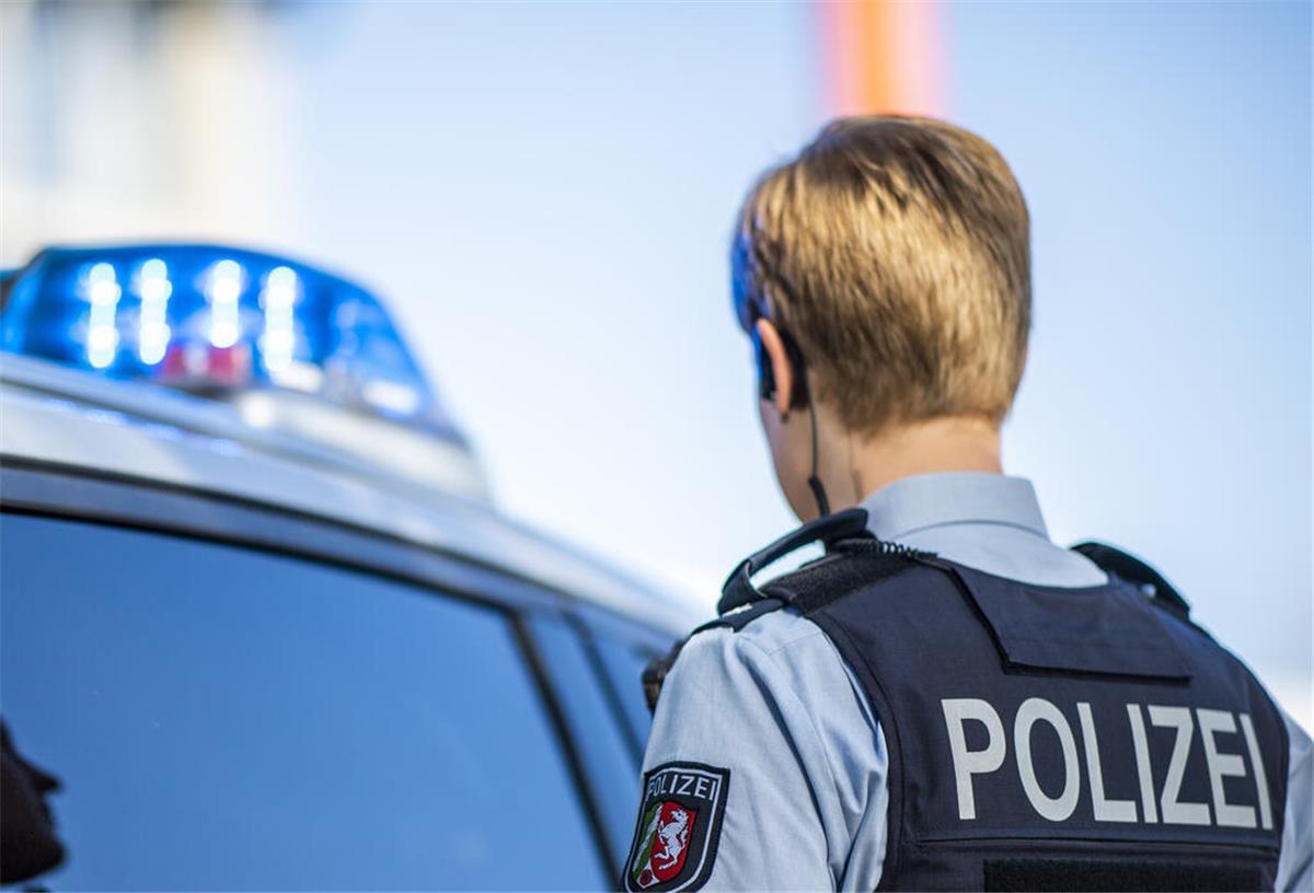 Tödlicher Unfall in Hagen: Polizei fasst flüchtigen Fahrer Eine Polizistin steht vor einem Streifenwagen, dessen Blaulicht leuchtet
