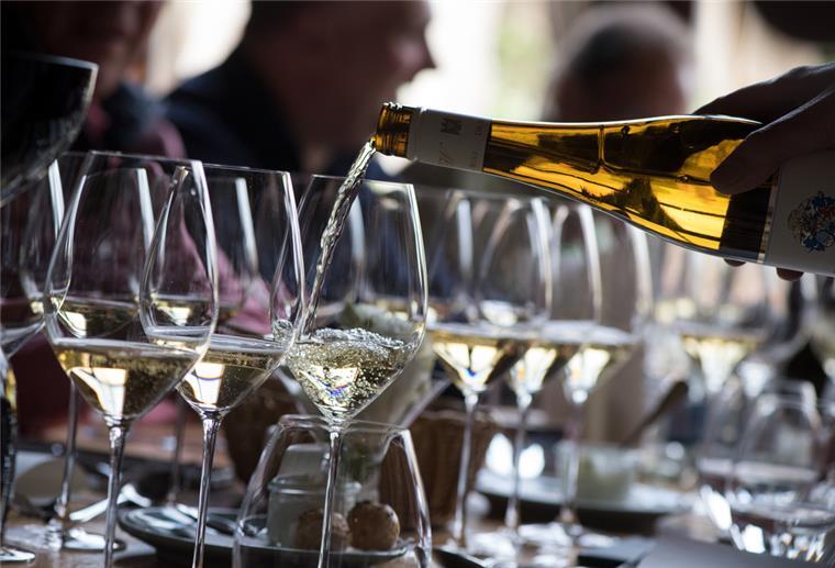 Wein wird aus einer Flasche in Gläser gegossen.