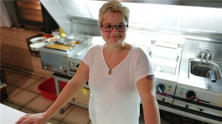 Eine Frau steht in einer Imbissküche.