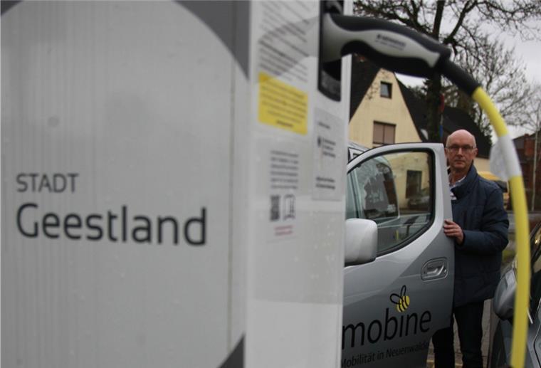 Ein Mann steht neben einem Auto.