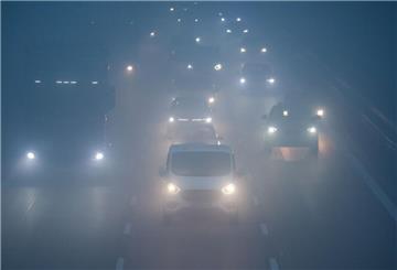 Bei Nebel und schlechter Sicht fahren am frühen Morgen Pkw und Lkw über die Autobahn.