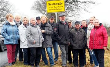 Neuenwalder Einwohner stellen sich vor ihr Ortsschild. Ortsbürgermeisterin
 Ellen Frank (rechts) ist stolz auf den Ort, "der alles hat". 