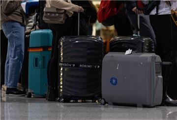 Passagiere mit Koffern warten am Check-In Schalter am Frankfurter Flughafen.
