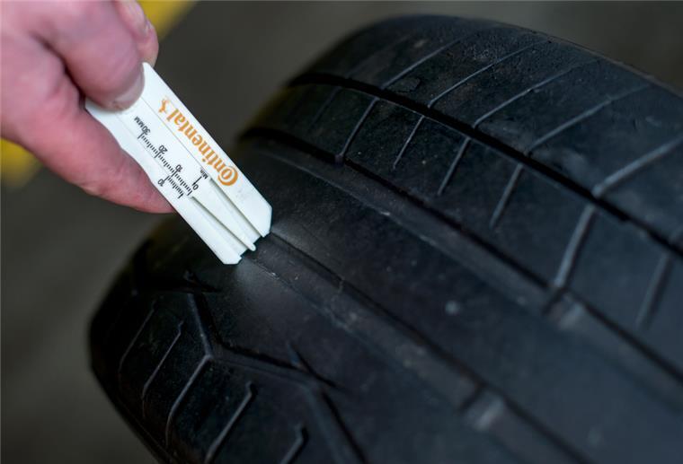 Alte Reifen ausmustern: Das muss beachtet werden Ein Kfz-Mechaniker misst die geringe Profiltiefe eines abgefahrenen Reifens