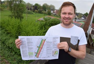 Nico Wefer, bei der Firma Thieling als Projektleiter tätig, hält in seinen Händen den Bebauungsplan für die Wohnanlage Hansings Gärten. Auf dem Gelände hinter ihm sollen ab Frühjahr 2023 die ersten 30 bis 35 Wohneinheiten entstehen.