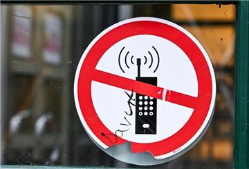 Ein Schild mit einem durchgestrichenen Handy-Symbol weist in einer Schule auf das Handyverbot hin.