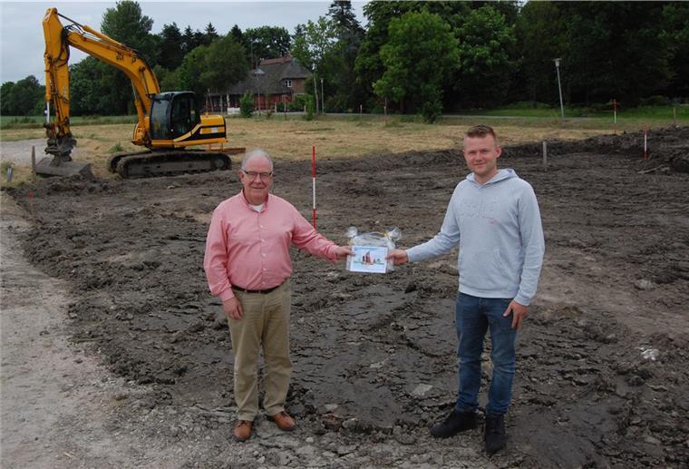 Baugebiet Schwei: Der erste Bauherr hat losgelegt Niels Müller (rechts) ist der erste Bauherr im Baugebiet Schwei. Er hat auf seinem Grundstück bereits losgelegt. Bürgermeister Klaus Rübesamen begrüßte ihn mit einem Gutschein.