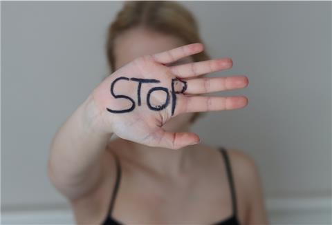 Eine junge Frau zeigt ihre Hand, auf der das Wort STOP steht.