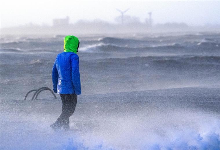 Nordsee im Klimafieber: So heftig trifft es unsere Küste Eine Person steht an der Küste und beobachtet eine Sturmflut.