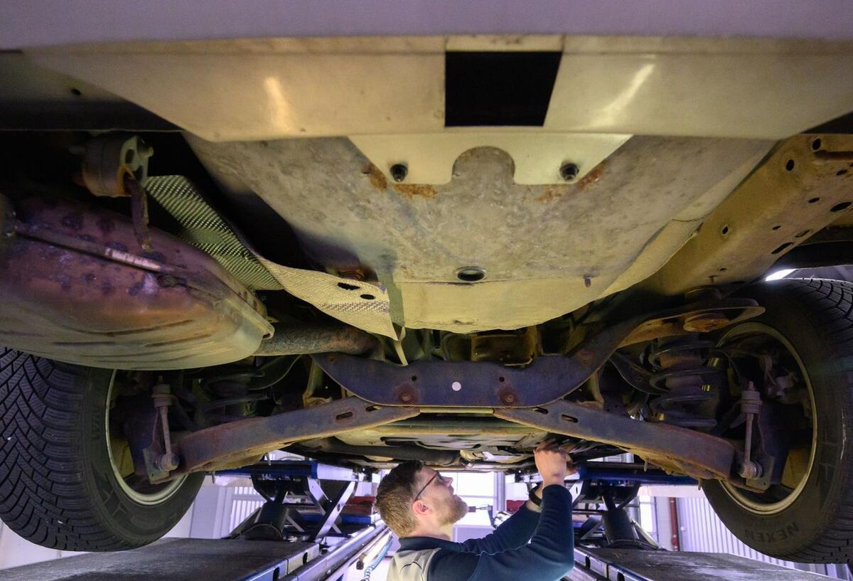 TÜV bald jährlich? Bundesland wehrt sich gegen EU-Pläne Ein TÜV Mitarbeiter schraubt an einem Auto.