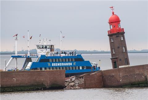 Die Weserfähre fährt an dem schiefen Moleturm vorbei.