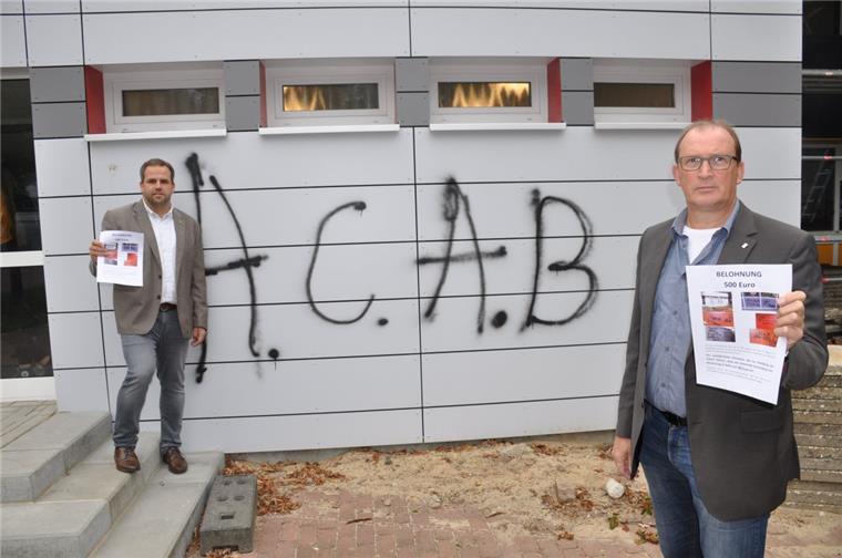 Ob Fenster oder Fassaden: Der unbekannte Graffiti-Sprayer hat allein an sieben Wänden der Hauptstelle der Oste-Hamme-Schule seine Spuren hinterlassen. Bürgermeister Axel Renken (rechts) und Geschäftsbereichsleiter Marcel van der Pütten hoffen, dass mit einer Belohnung der Täter ermittelt werden kann. Die Abkürzung ACAB steht für die englischsprachige Version der Parole „Alle Polizisten sind Bastarde“.