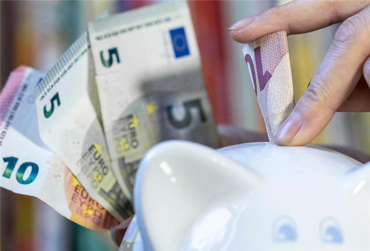 Geld sparen im Sommer: So klappt es mit einfachen Haushalts-Tricks Eine Frau steckt einen 10 Euroschein in ein Sparschwein.