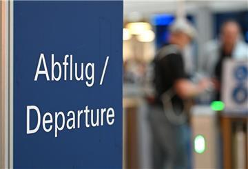 Flugreisende stehen an der Sicherheitskontrolle an einem Flughafen. 