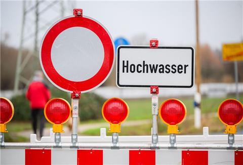 Ein Warnschild «Hochwasser» steht an einer Straßensperre.