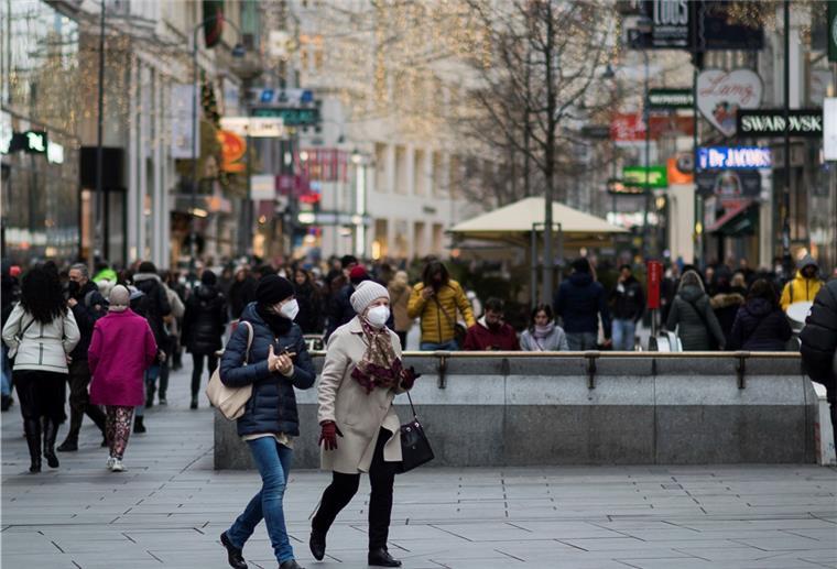 Ganz Österreich ab Montag im Lockdown - Impfpflicht kommt Zwei Personen mit Mund-Nasen-Schutz gehen in Wien, Österreich, über eine Einkaufsstraße.