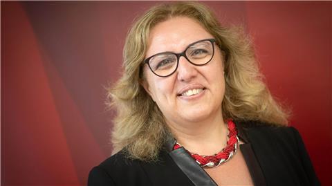 Özlem Ünsal (SPD), Senatorin für Bau, Verkehr und Stadtentwicklung, steht vor einer roten Wand.