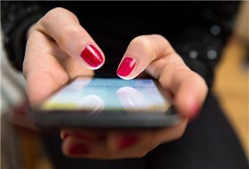Eine Frau mit rotem Nagellack tippt auf einem Smartphone.