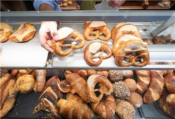 Ein Hand nimmt in einer Bäckerei eine Brezel aus einer Auslage. Ein Bäckerbesuch kann demnächst teure Folgen haben. 