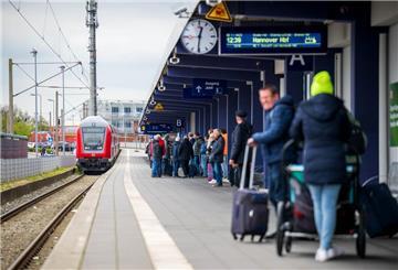 Touristen laufen mit Rollkoffern am Bahnhof Norddeich-Mole entlang.