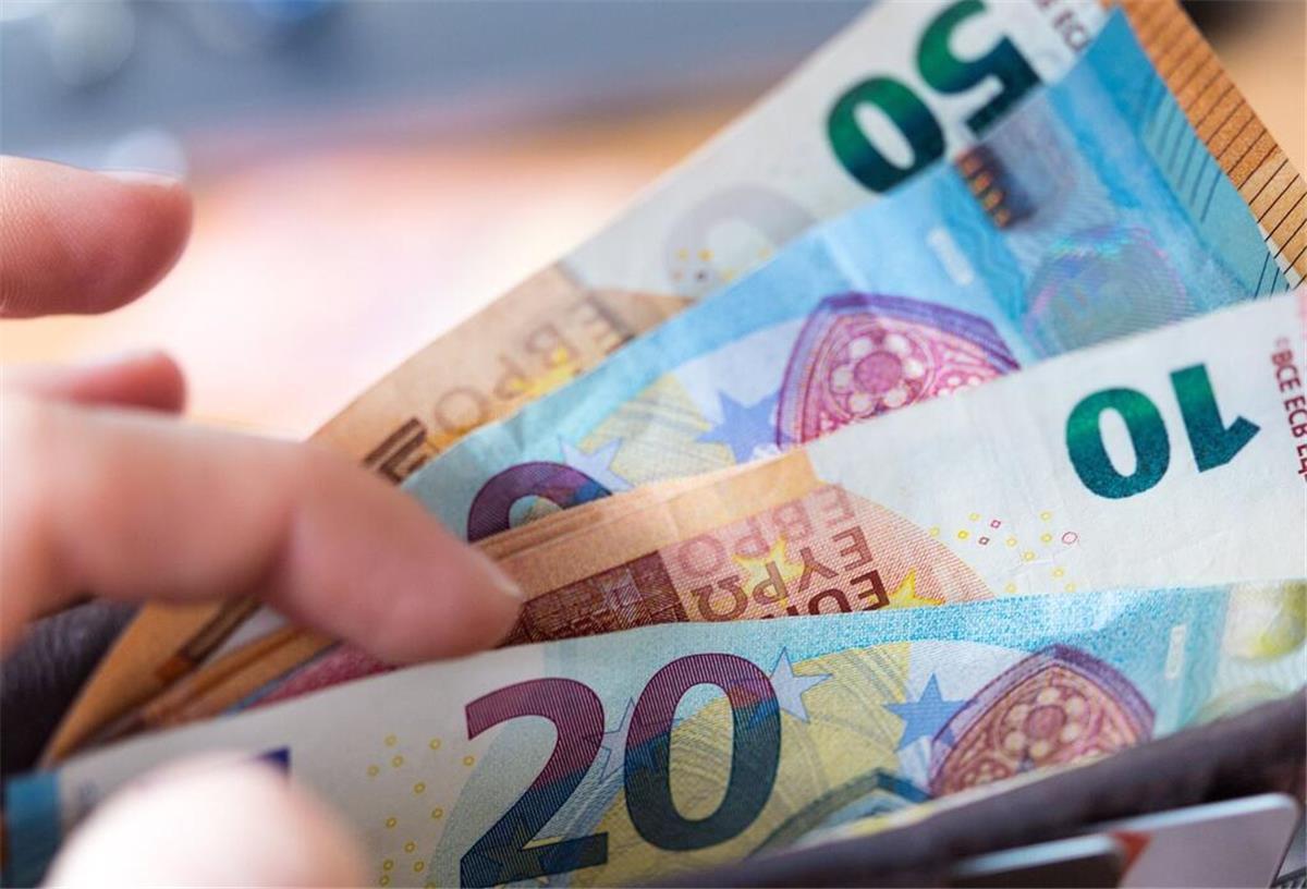 Hunderte Euro pro Jahr! Neue Pauschale entlastet Pendler enorm Eine Hand zieht Geldscheine aus einem Geldbeutel. Pendeln lohnt sich bald mehr! Die Pauschale soll ab dem ersten Kilometer steigen – besonders Kurzstrecken-Pendler profitieren.