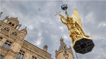 Per Kran wird der Erzengel Michael nach mehrmonatigen Sanierungsarbeiten zurück auf die Kuppel des Schweriner Schlosses befördert.